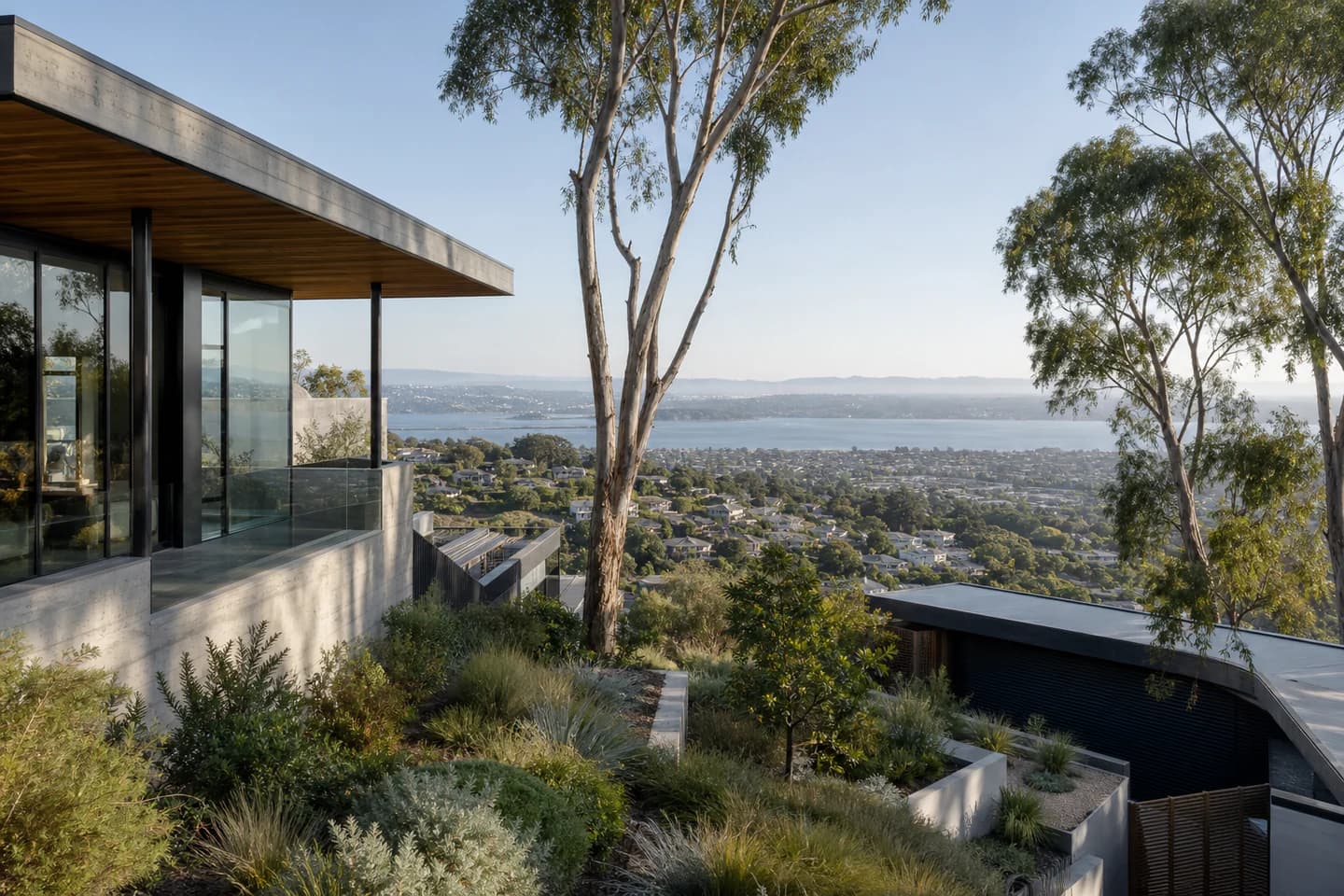 Editorial Bay Area residential context with hillside architecture, mature planting, and distant water; not an exact property or listing